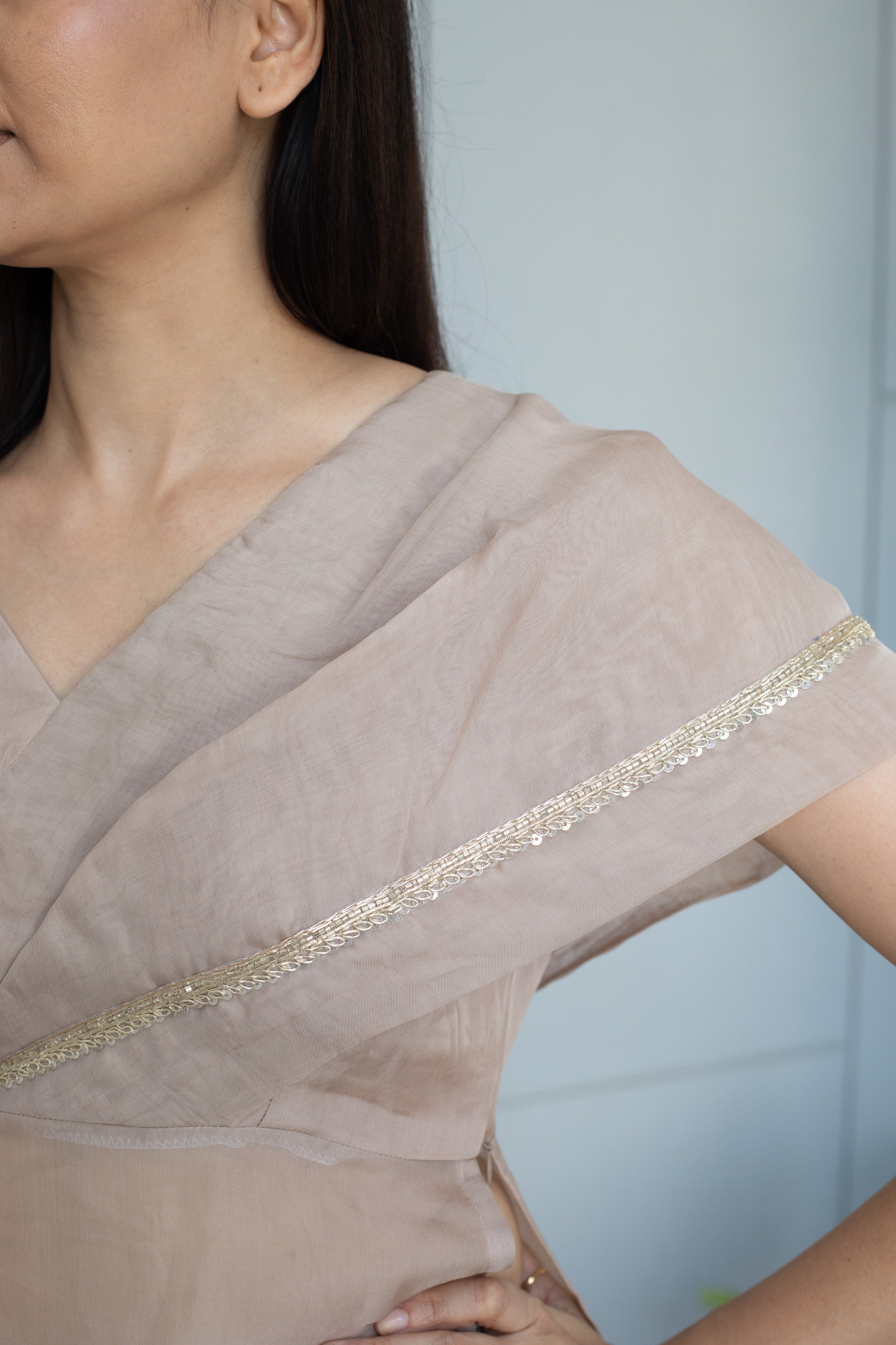 Woman wearing a beige dress with lace trim against a light blue background