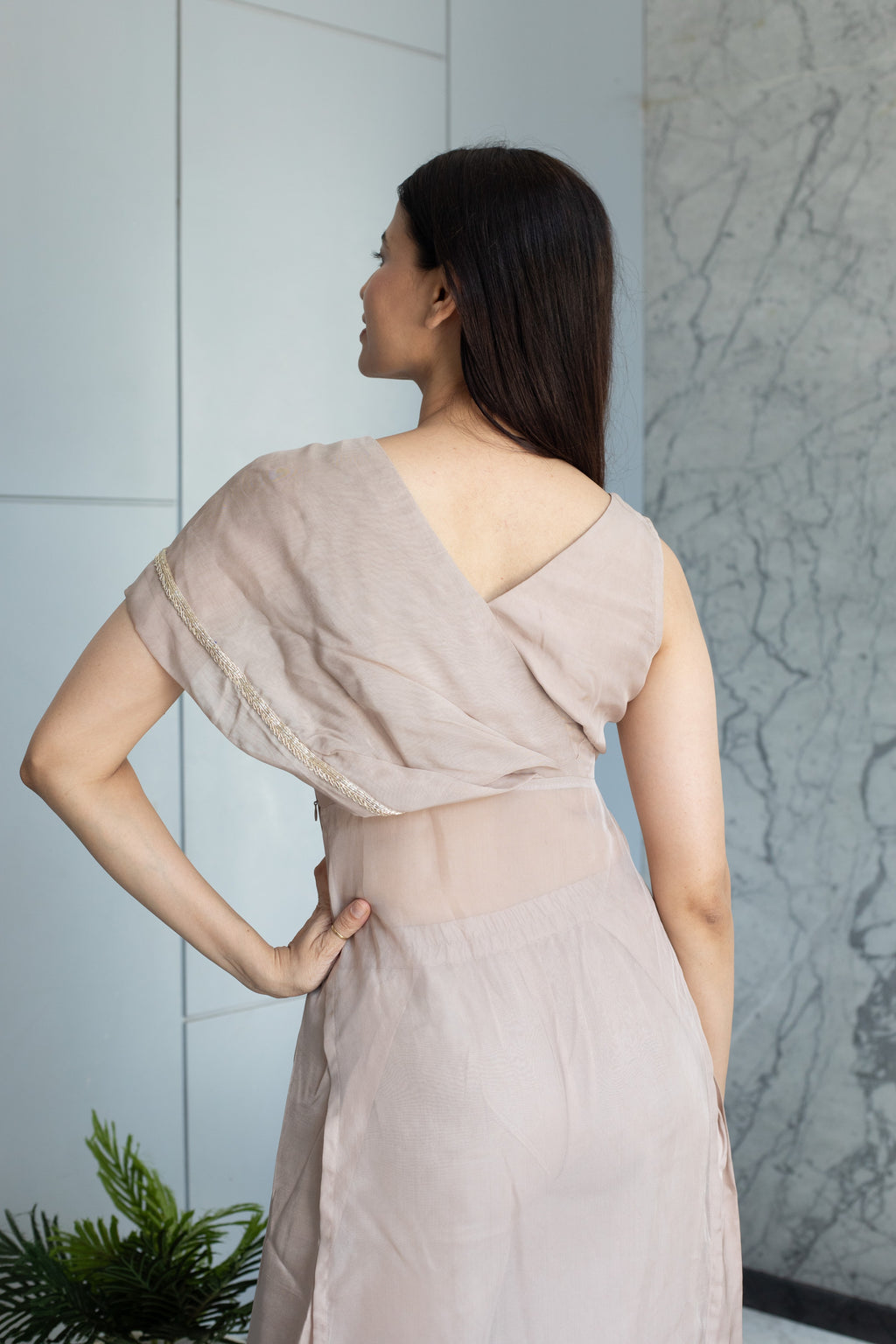 Woman in a light pink dress lying on a marble floor with a white wall in the background