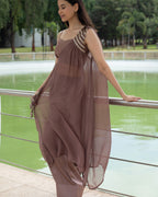 Woman in a flowing dress standing by a railing with a scenic background