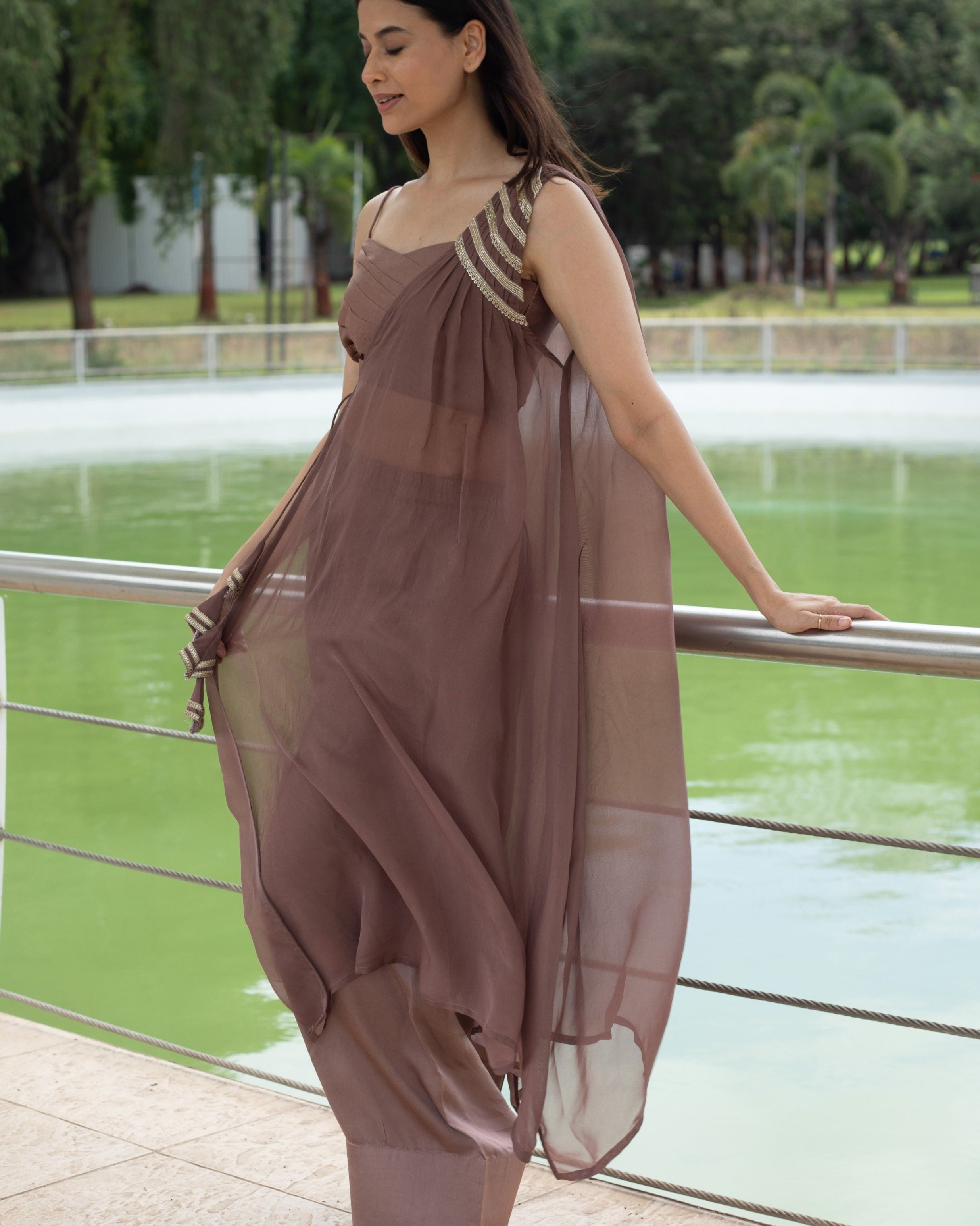 Woman in a flowing dress standing by a railing with a scenic background