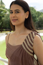 Woman wearing a brown dress with gold detailing outdoors