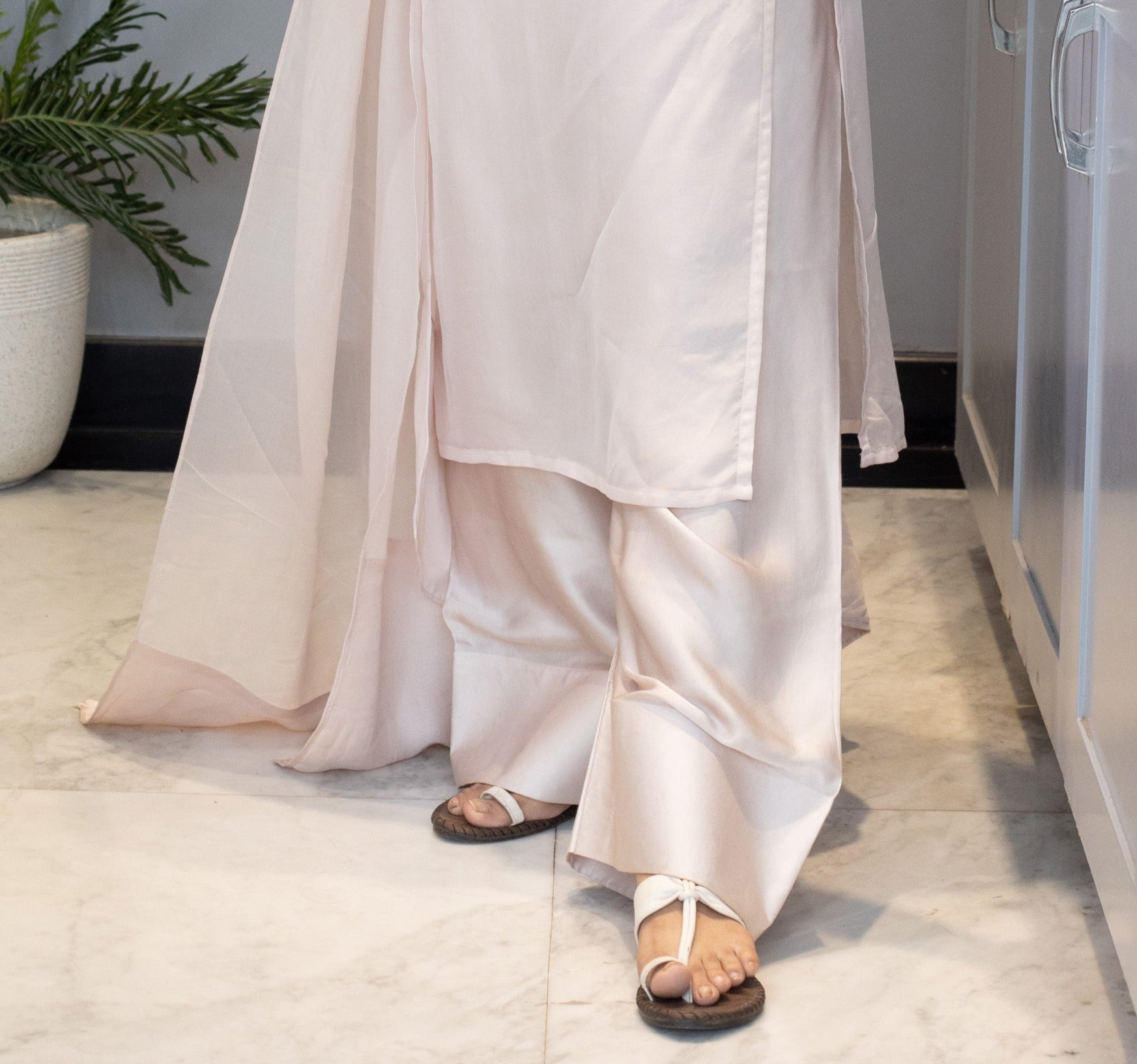 Woman in a white dress standing next to a washing machine in a kitchen.
