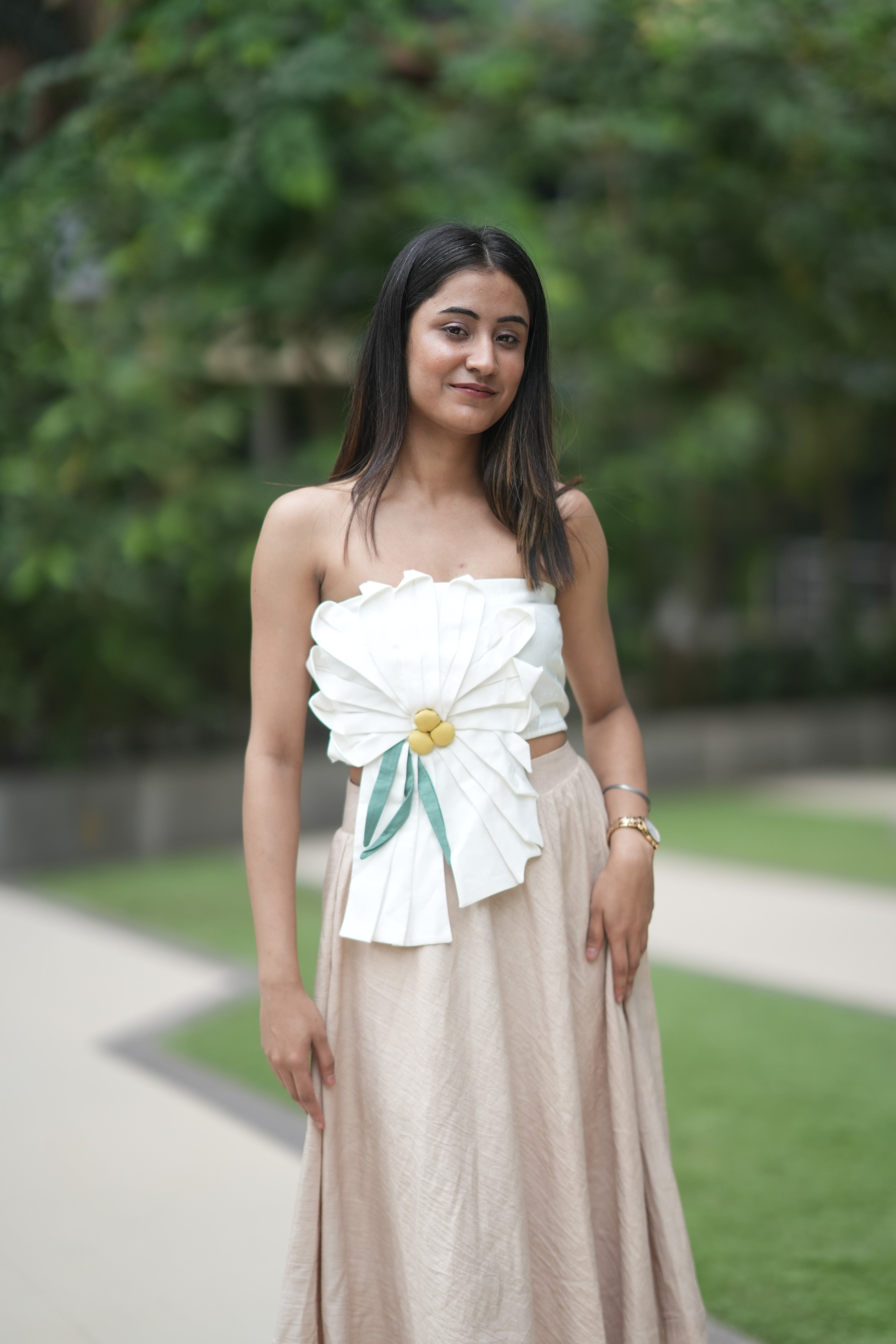 Woman wearing a white top with floral design and beige skirt outdoors
